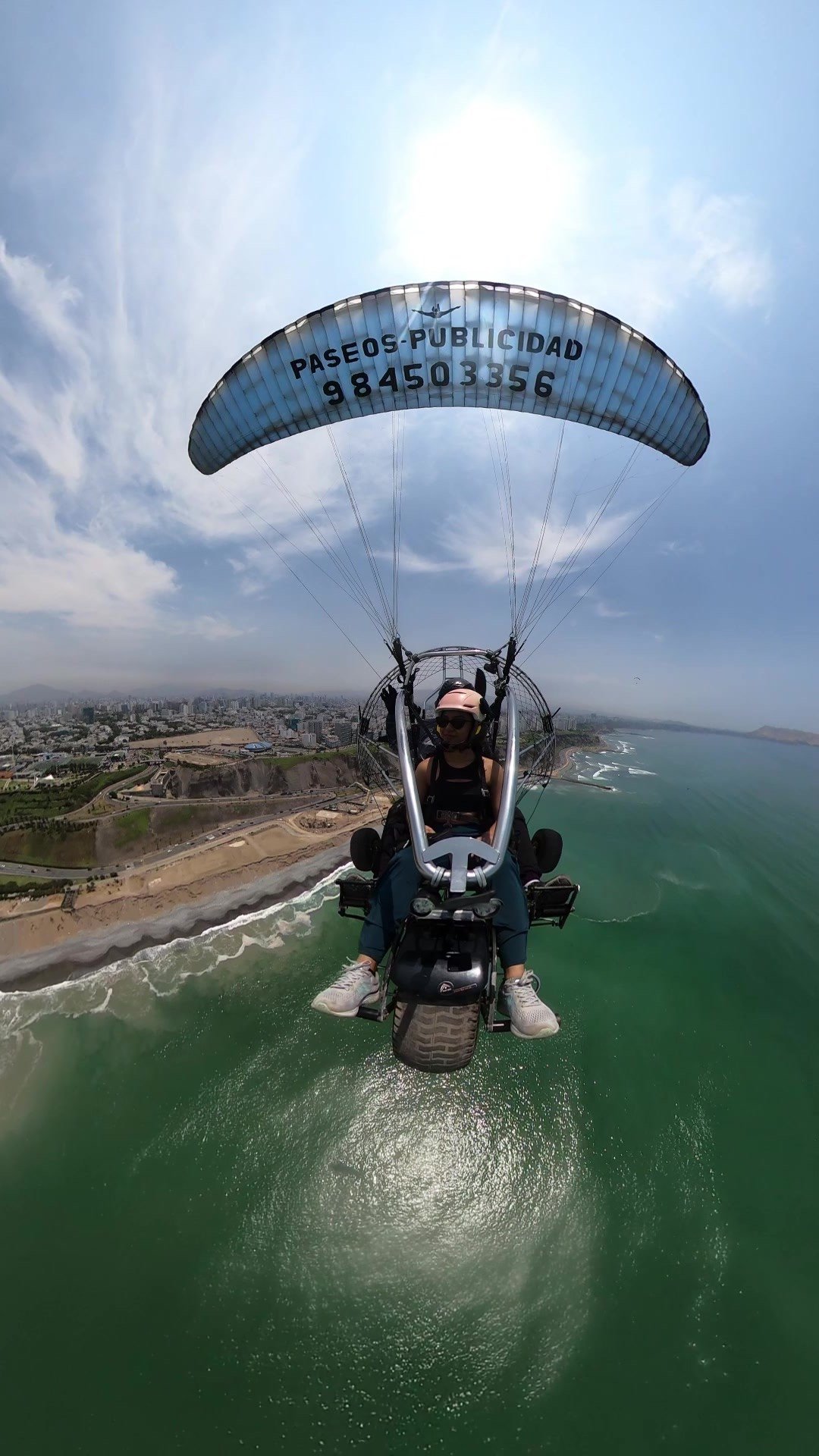 Paratrike volando sobre el mar Pacífico en la Costa Verde de Lima con vista aérea de la ciudad