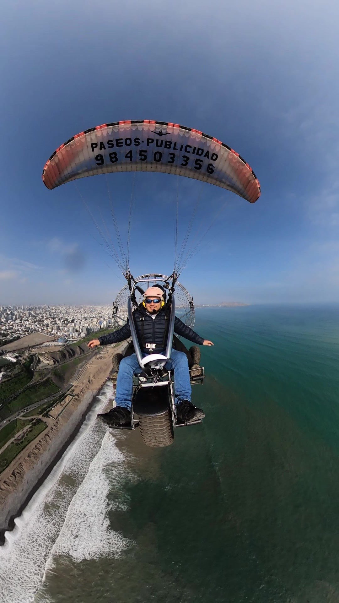 Turista disfrutando vuelo en paratrike sobre el océano Pacífico y la Costa Verde de Lima